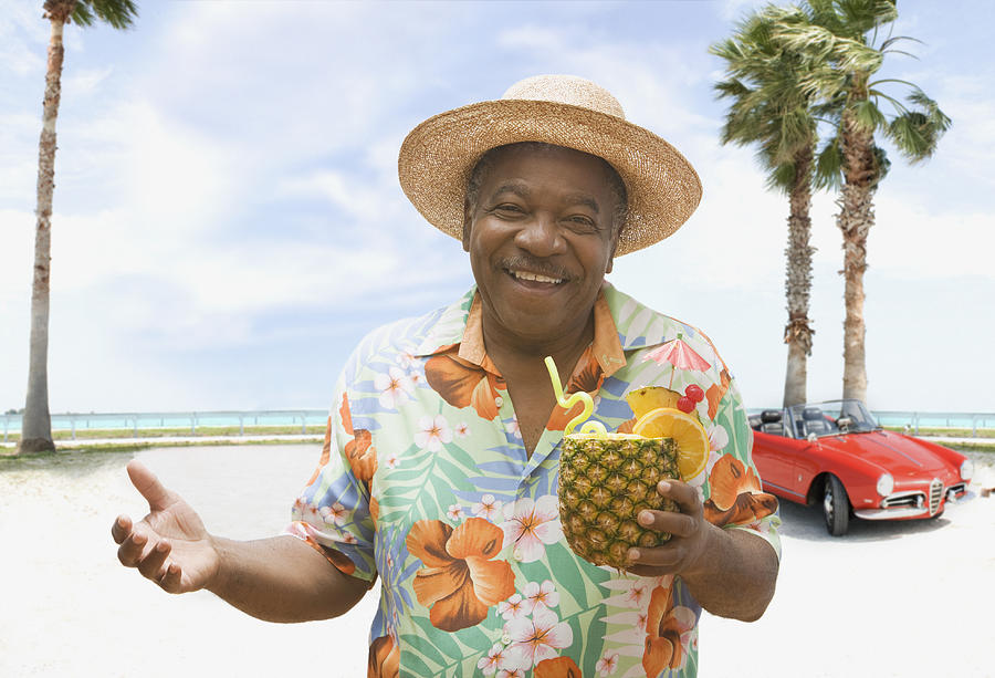 African man holding pineapple drink on tropical beach Photograph by Jose Luis Pelaez Inc