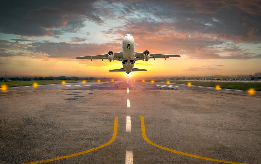 Airplane taking off from the airport runway in beautiful sunset light Photograph by Issarawat Tattong