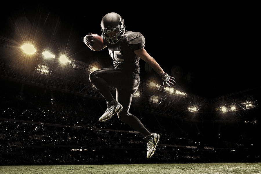 American football sportsman player on stadium running in action. Sport wallpaper with copyspace. Photograph by Anton5146