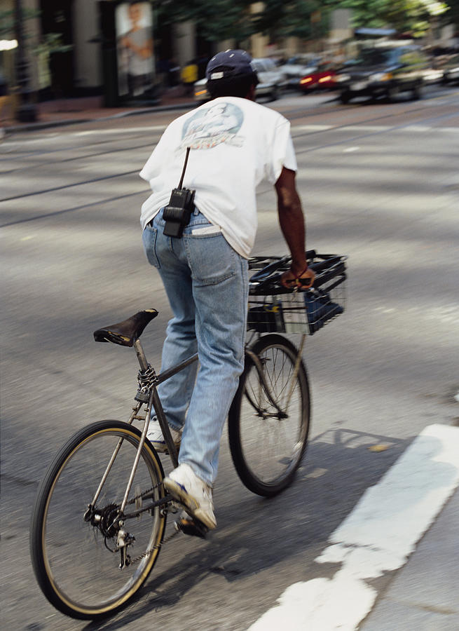 An African American Courier Rides A Bike To Deliver A Package Photograph by Photodisc