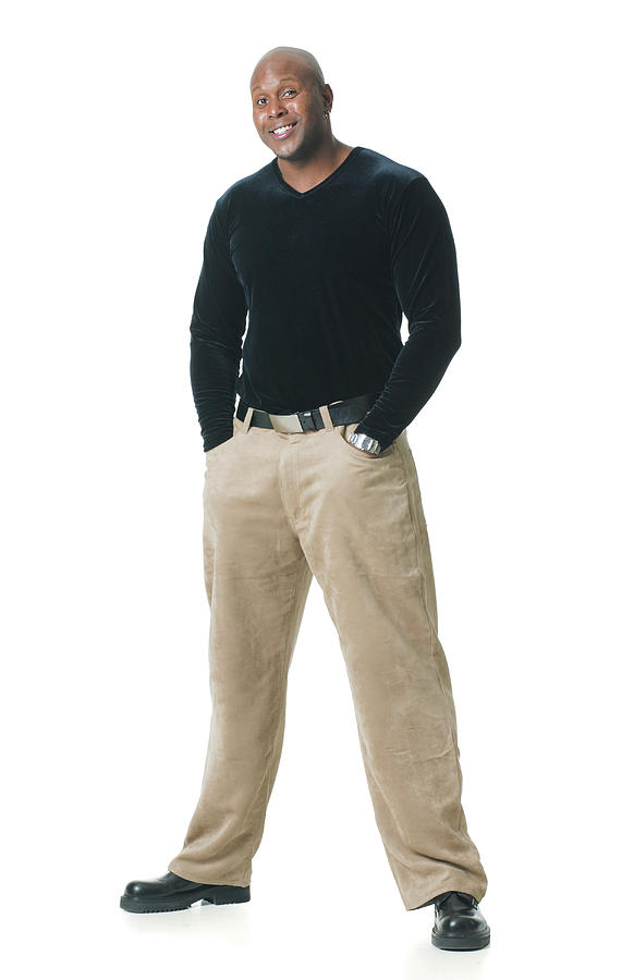 An African American Man In Tan Pants And A Black Shirt Puts His Hands In His Pockets And Smiles Photograph by Photodisc