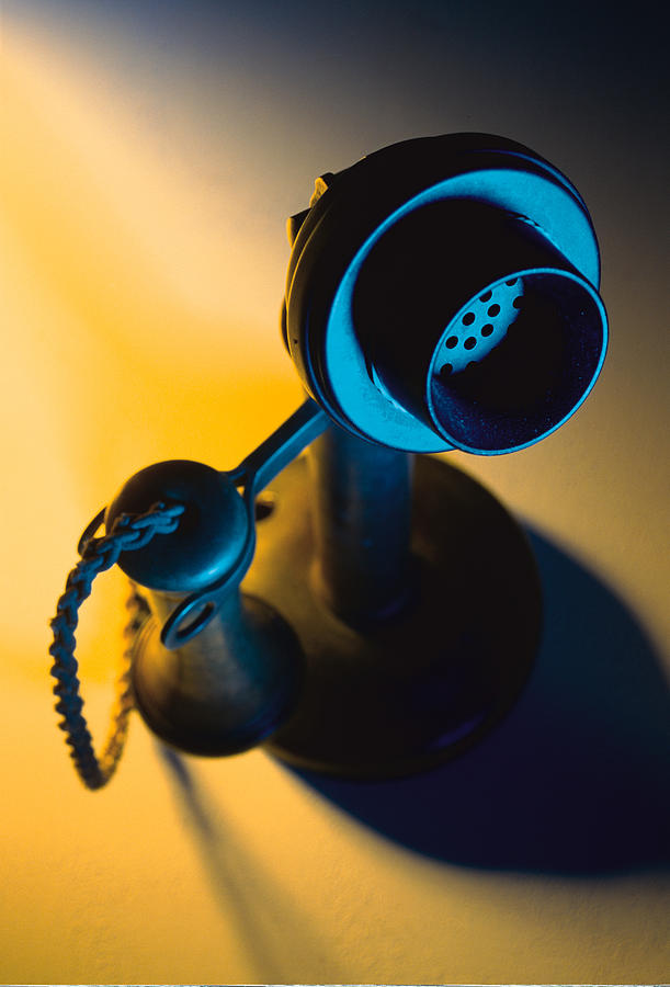 An Antique Phone With Separate Receivers For Mouth Piece And Speaker Stands In The Middle Of A Yellow Light Photograph by Photodisc