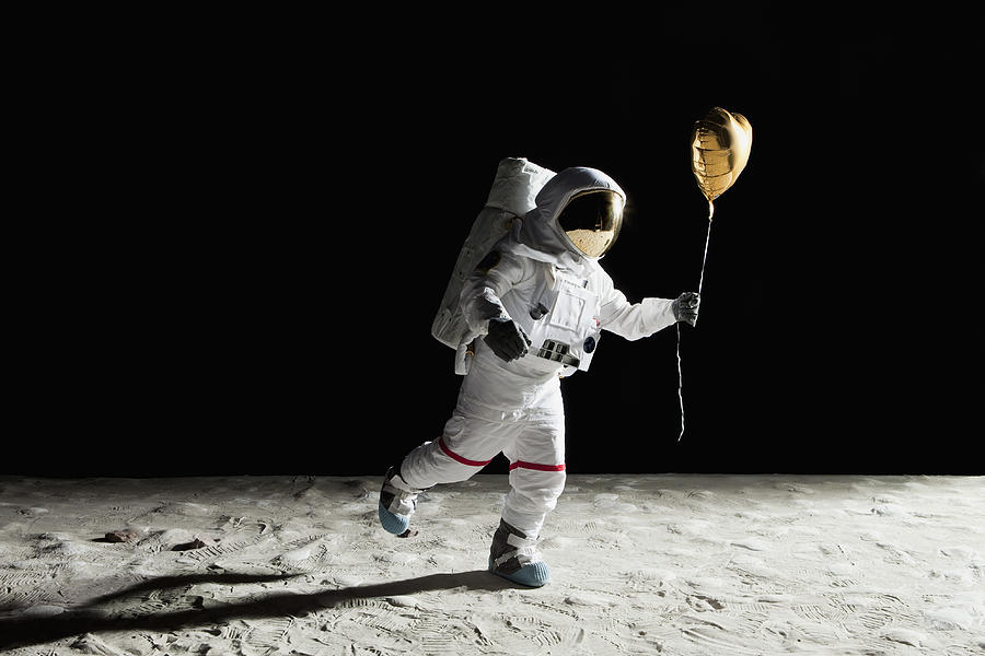 An astronaut on the moon holding a heart shaped helium balloon Photograph by fStop Images - Caspar Benson