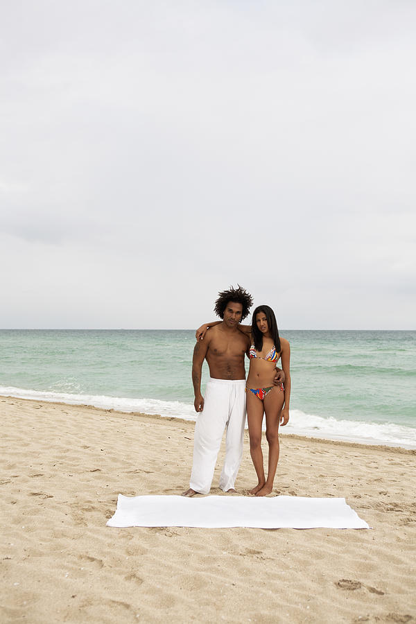 An attractive young couple standing on a beach Photograph by Emiliano Granado