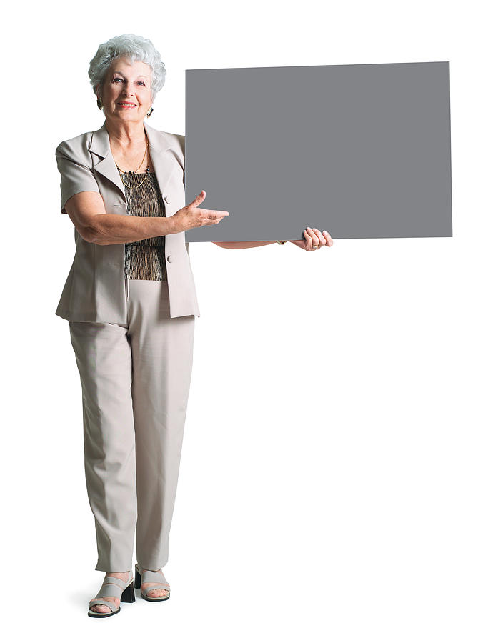 An Elderly Caucasian Woman In A Tan Pant Suit Holds A Sign To Her Side And Smiles Photograph by Photodisc