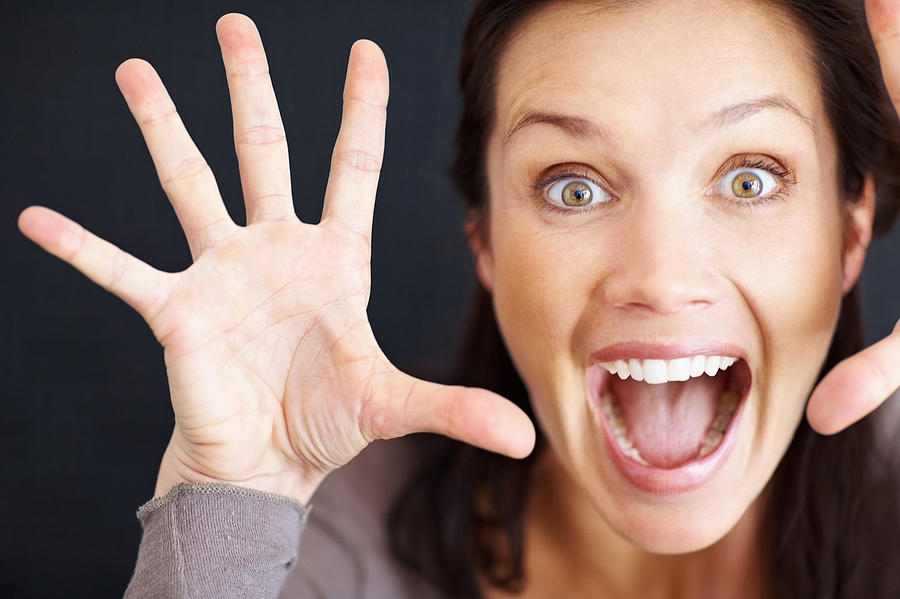 An excited middle aged woman screaming against black background Photograph by GlobalStock