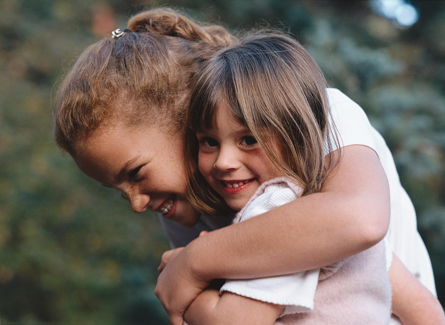 An Older Sister Gives Her Baby Sister A Big Hug Photograph by Photodisc