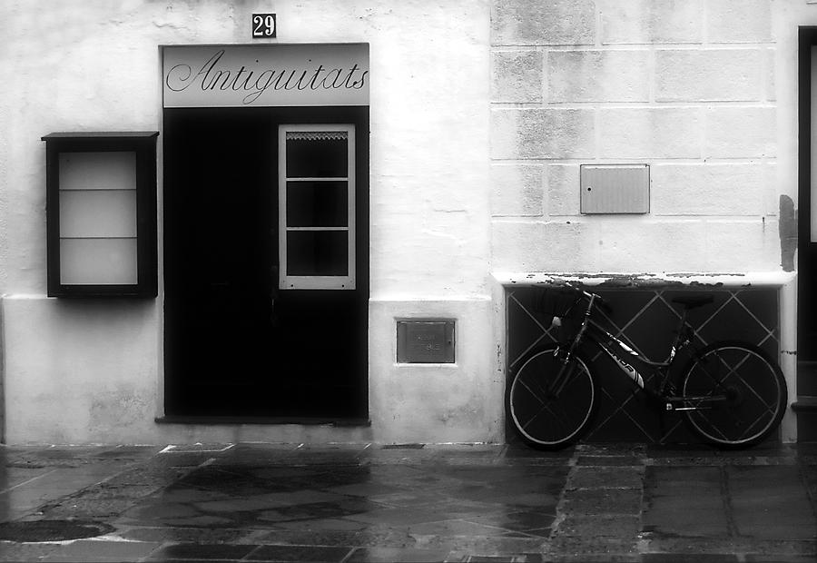 Old village street with an antique shop and a bike remember us past times in Es Mercadal - Menorca Photograph by Pedro Cardona Llambias