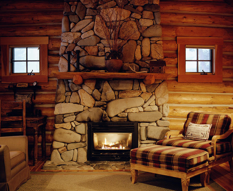 Armchair beside stone fireplace in log cabin Photograph by Ryan McVay