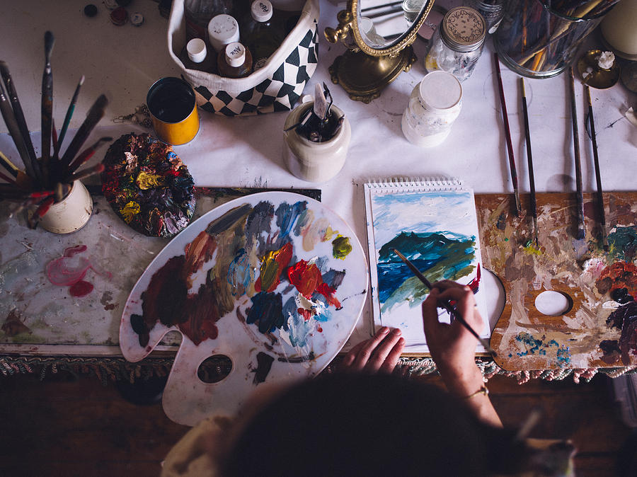 Artist painting on paper with a palette and bright colors Photograph by Wundervisuals