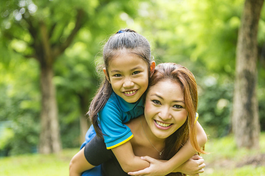 Asian Mother and Daughter Piggybacking Together in the Park Photograph by Davidf