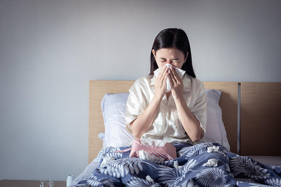 Asian woman have a cold, sitting on cozy bed using tissue for snot. sick at home Photograph by Asiandelight Asian woman have a cold, sitting on cozy bed using tissue for snot. sick at home Photograph by Asiandelight