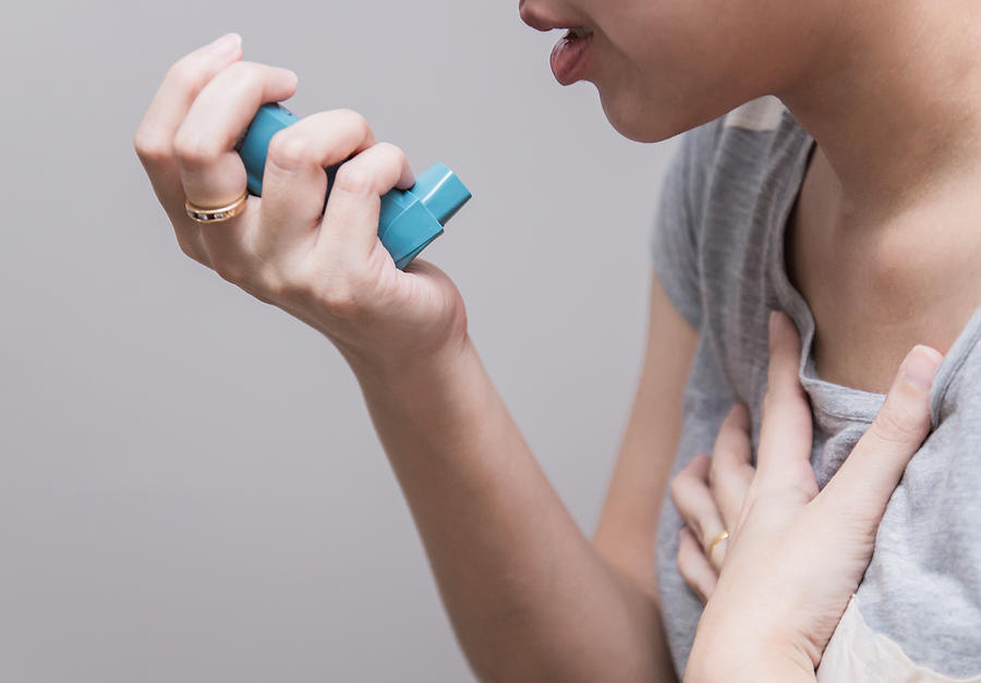Asian woman using a pressurized cartridge inhaler extended pharynx, Bronchodilator Photograph by Catinsyrup