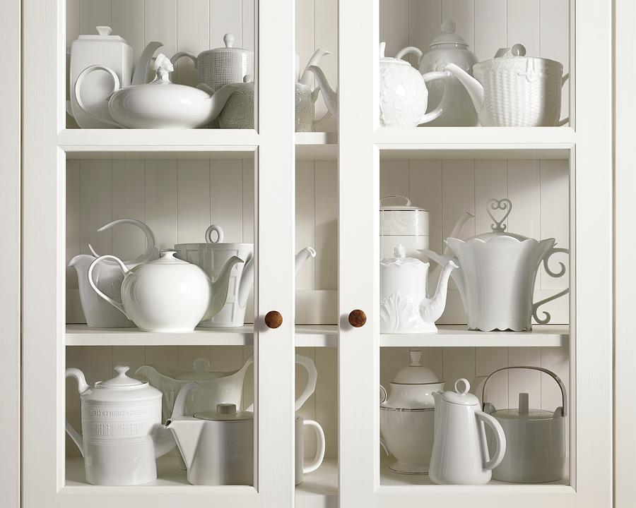 Assorted Tea And Coffee Pots In A Glass Cupboard Photograph by Sivan Lewin