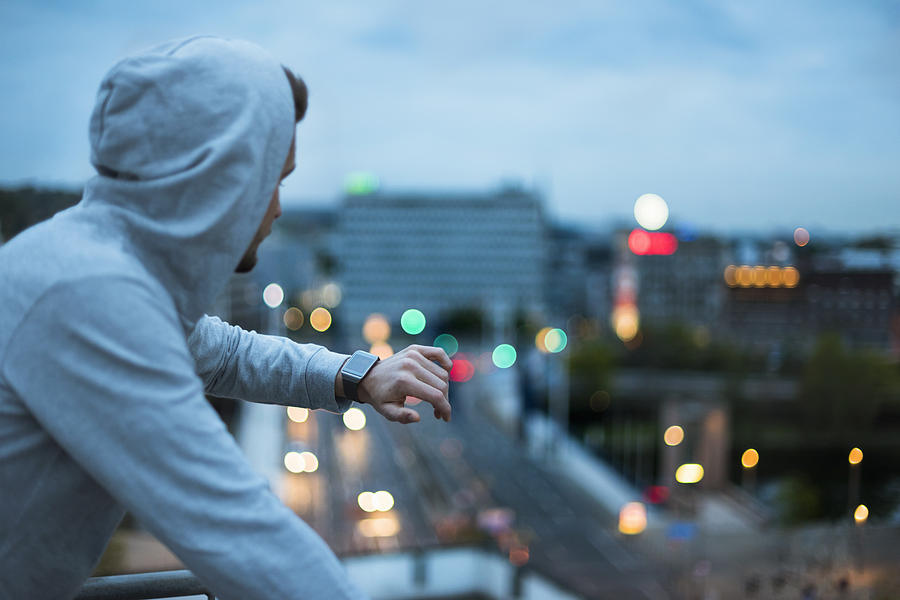 Athlete checking his smartwatch above the city at dawn Photograph by Westend61