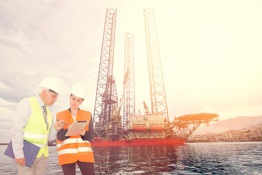 Attractive young female engineer and her boss, Offshore construction platform Photograph by 1001Love