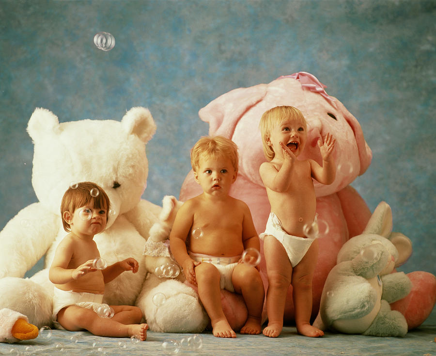 Babies (9-12 months) sitting on stuffed animals playing with bubbles Photograph by Getty Images