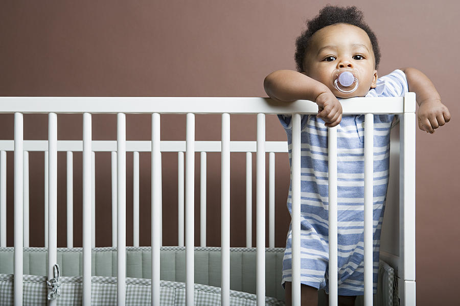 Baby boy standing in cot Photograph by Image Source