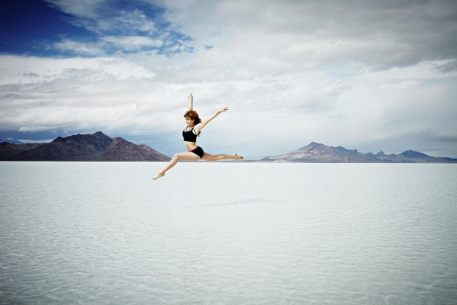 Ballerina Leaping In Mid-air Over Lake Photograph by Thomas Barwick