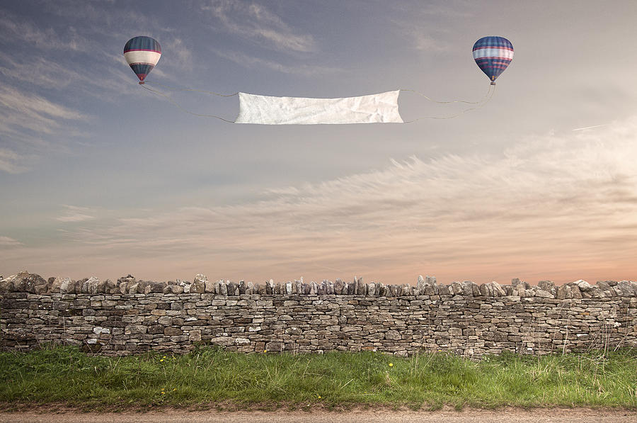 Banner between two hot air balloons over a Cotswold stone wall Photograph by Matt Walford