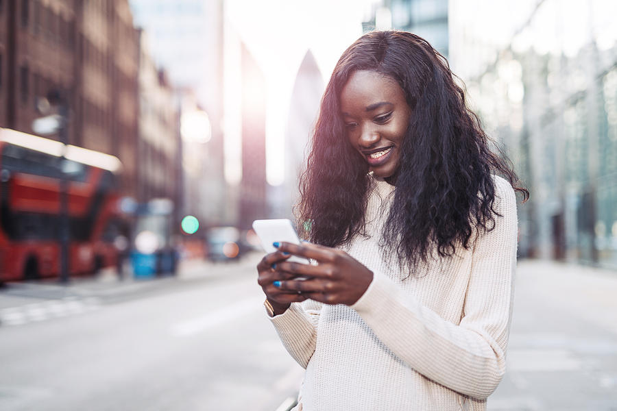 Beautiful black woman using phone in downtown to call crowdsourced taxi Photograph by Drazen_