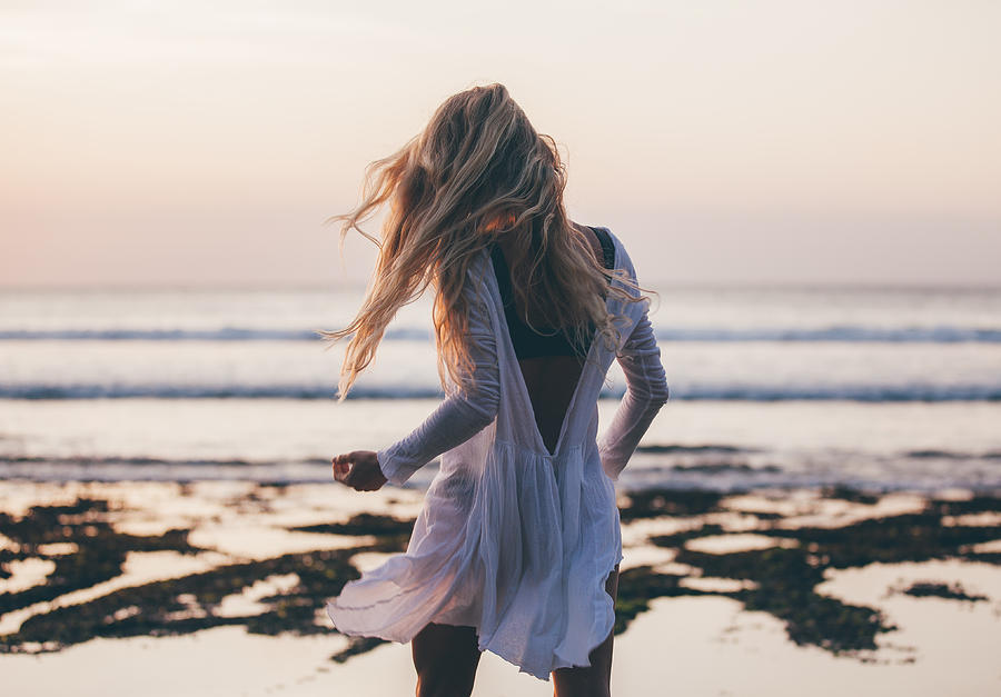 Beautiful blonde girl with long hair in short white dress dancing at sunset Photograph by Hagen Production