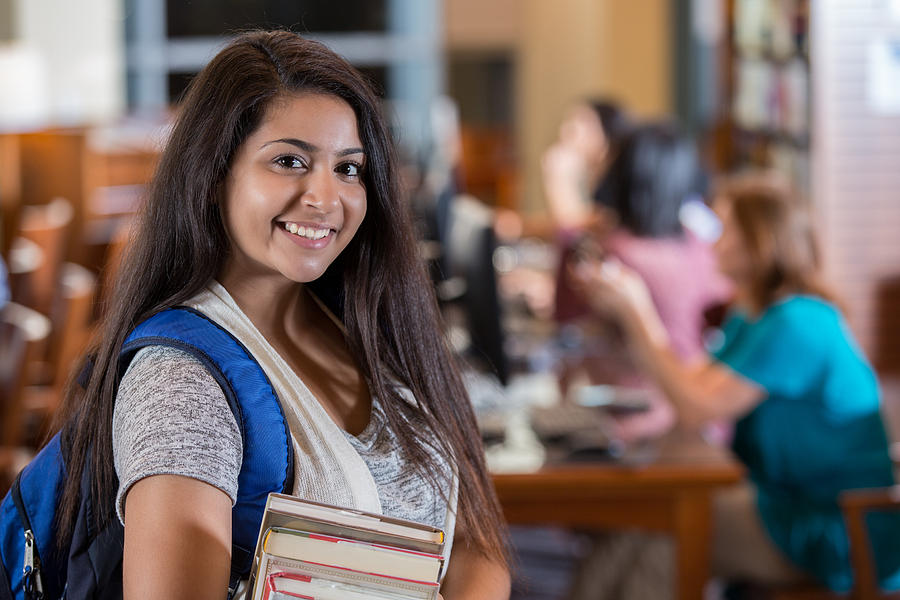 Beautiful Indian high school girl smiling in library before studying Photograph by Steve Debenport