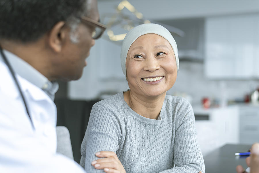 Beautiful Korean woman with cancer smiles at doctor Photograph by FatCamera