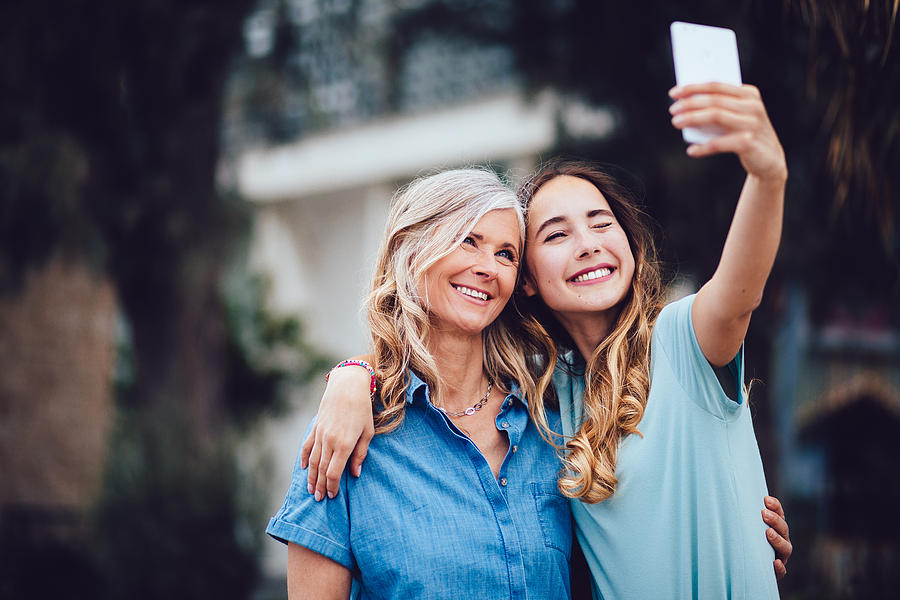 Beautiful mature mother and adult daughter taking selfies together Photograph by Wundervisuals