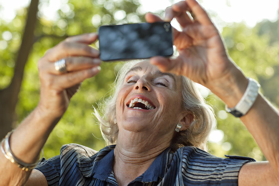 Beautiful Senior Woman taking photo using smartphone Photograph by Thomas_EyeDesign