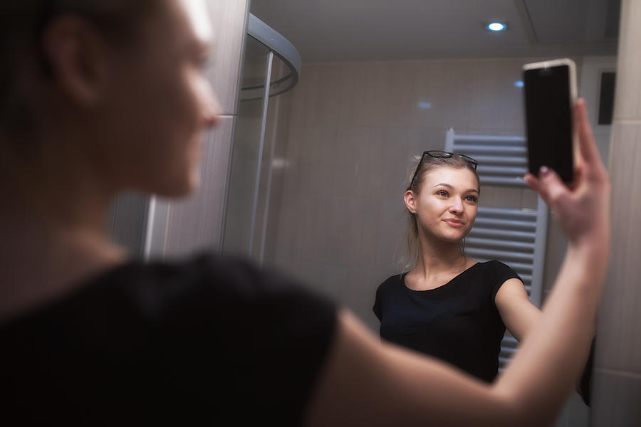 Beautiful Teenage Girl Taking a Selfie in Bathroom Photograph by CasarsaGuru