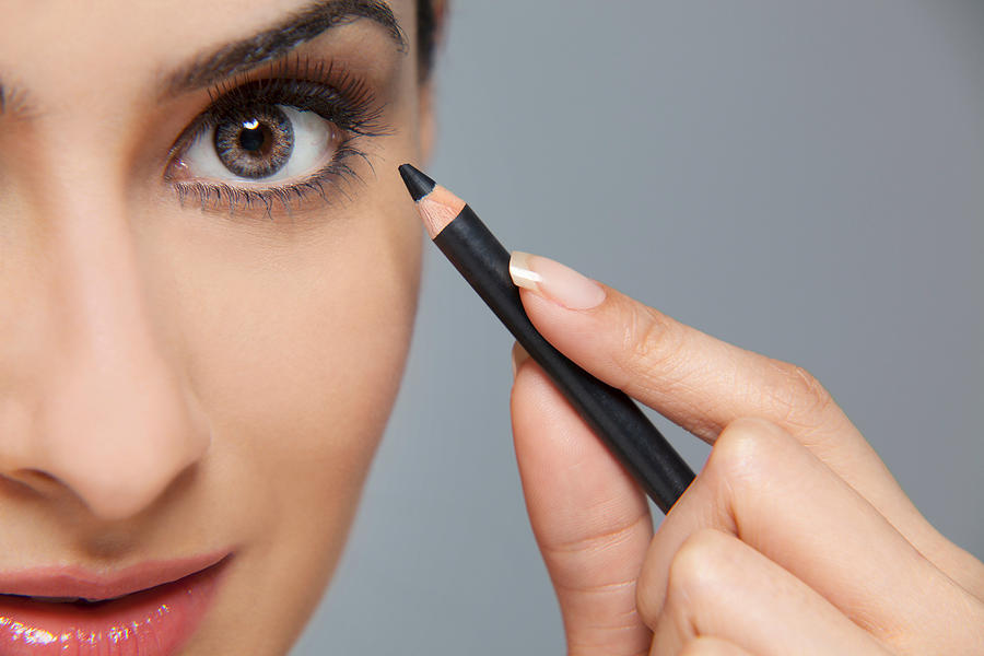 Beautiful woman applying eyeliner Photograph by Image Source
