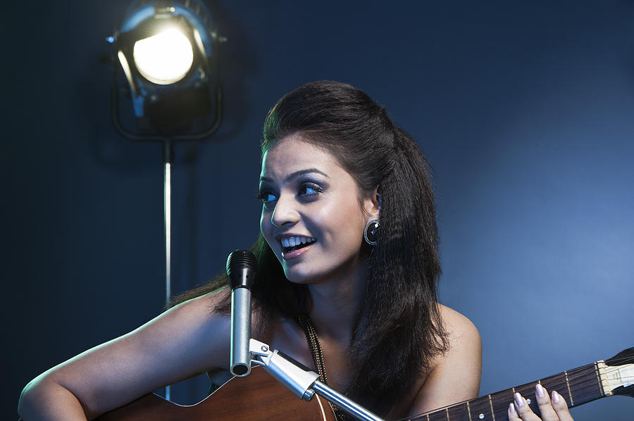 Beautiful young female singer performing with guitar on stage Photograph by Uniquely India