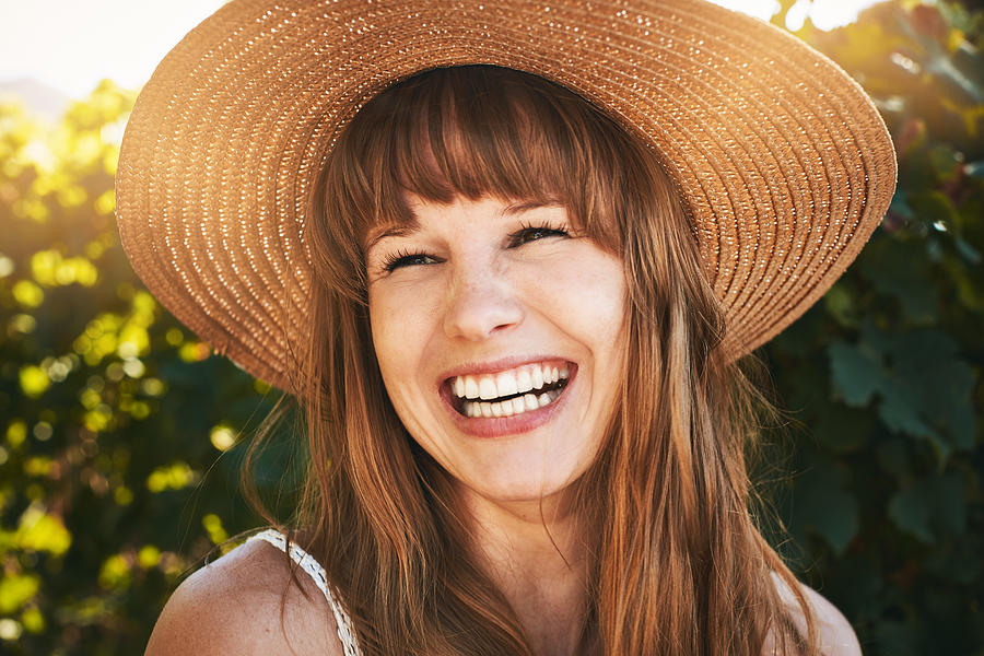Beautiful young redhead in straw sunhat laughs happily Photograph by RapidEye