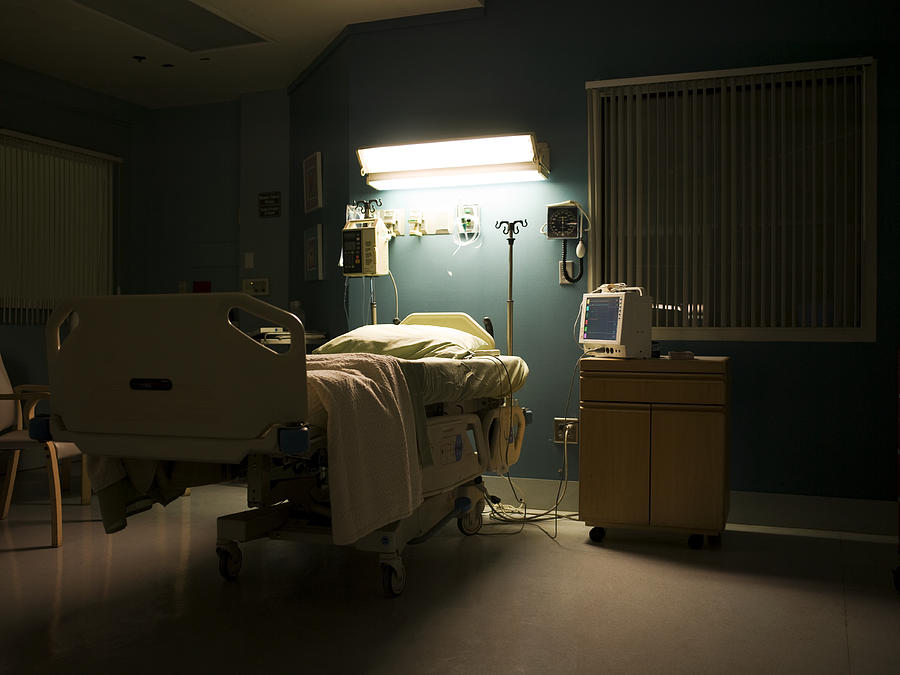 Bed in darkened empty hospital room Photograph by Thomas Northcut