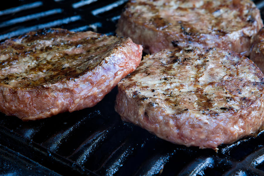 Beef quarterpounder burgers begin to cook on the gas barbecue ...