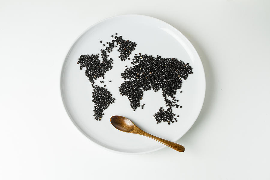 Beluga lentils on plate shaped like a world map with wooden spoon Photograph by Westend61