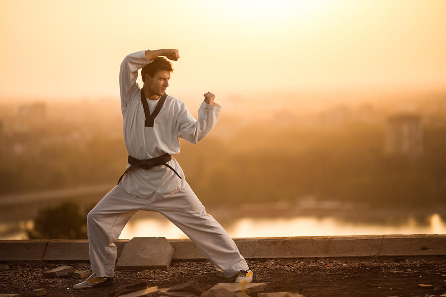 Black belt martial artist practicing karate at sunset. Photograph by Skynesher