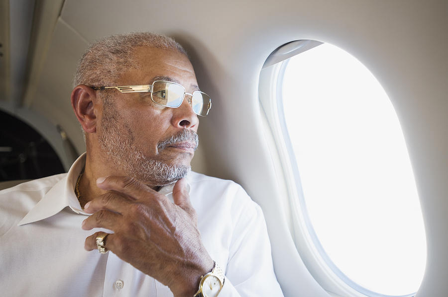 Black businessman looking out airplane window Photograph by Erik Isakson