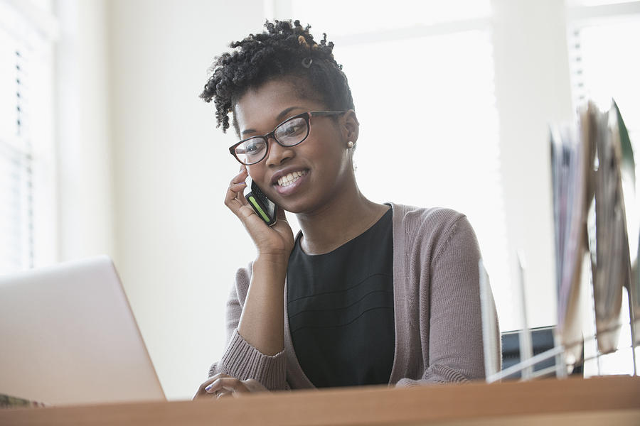 Black businesswoman talking on cell phone in office Photograph by Jose Luis Pelaez Inc