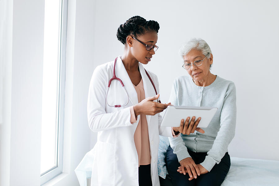 Black female doctor showing digital tablet to senior patient Photograph by Aldomurillo