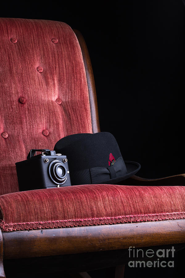 Still Life Photograph - Black hat vintage camera and antique red chair by Edward Fielding