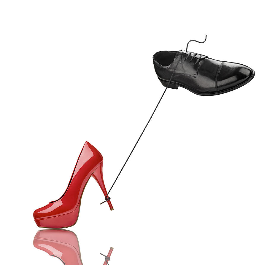 Black mans shoe and red high heel in front of white background Photograph by Westend61