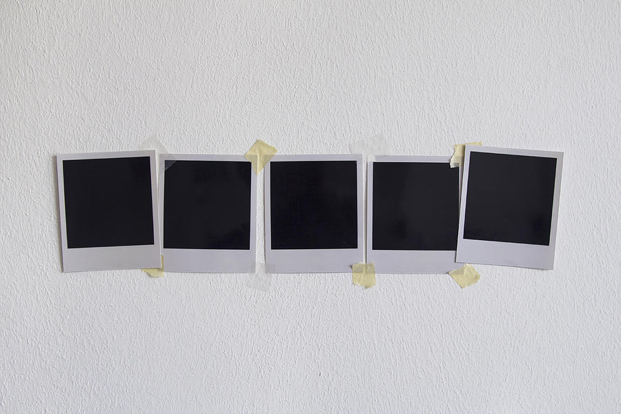 Blank instant camera prints stuck on white wall Photograph by Malte Mueller