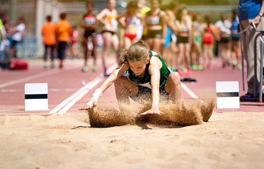 Blonde girl with pigtail landing on the sand in long jump Photograph by Sol de Zuasnabar Brebbia