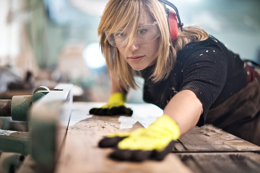 Blonde woman cutting a plank Photograph by Extreme-photographer