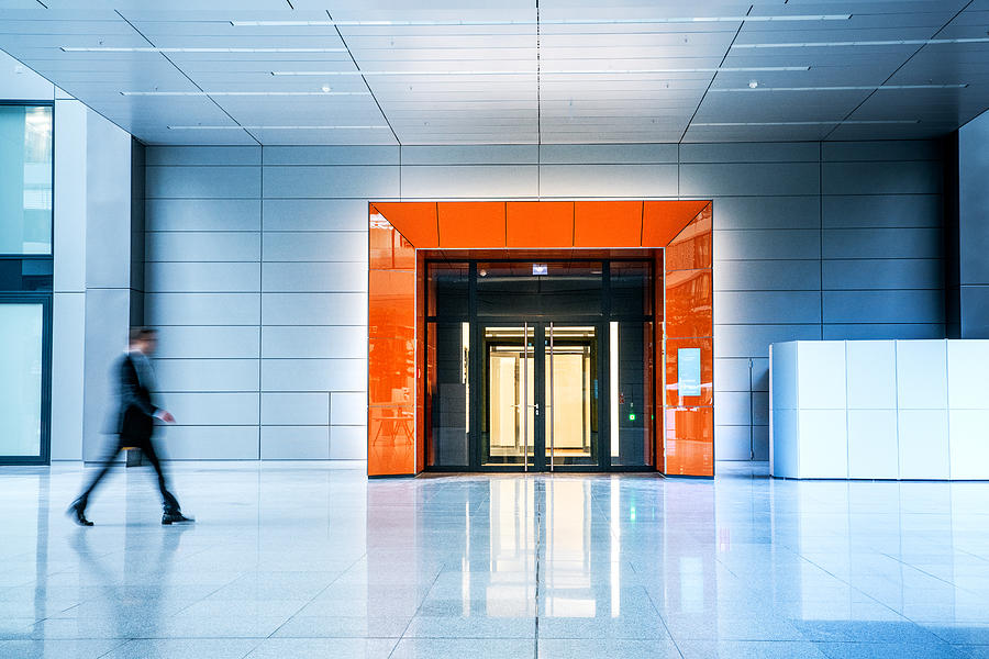 Blurred businessmen walking inside a modern building Photograph by Nikada