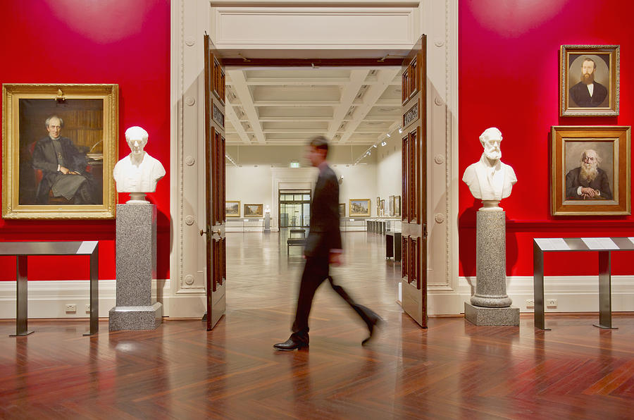 Blurred view of Caucasian security guard walking in art museum Photograph by Jacobs Stock Photography Ltd