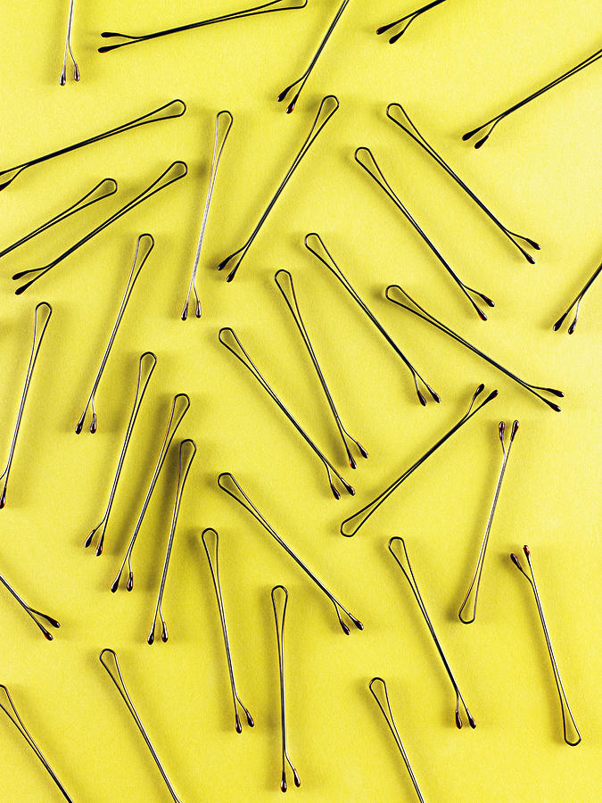 Bobby pins on a yellow surface. Photograph by Maren Caruso