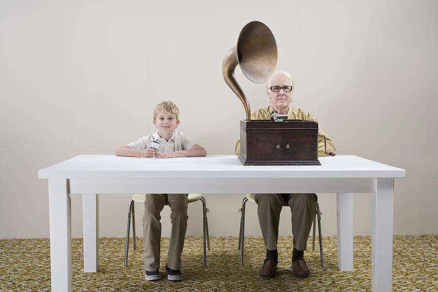 Boy (10-11) with mp3 player and man with gramophone sitting at table Photograph by Darrin Klimek